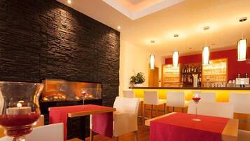 Un restaurante con pared de piedra, mesas rojas y sillas blancas.