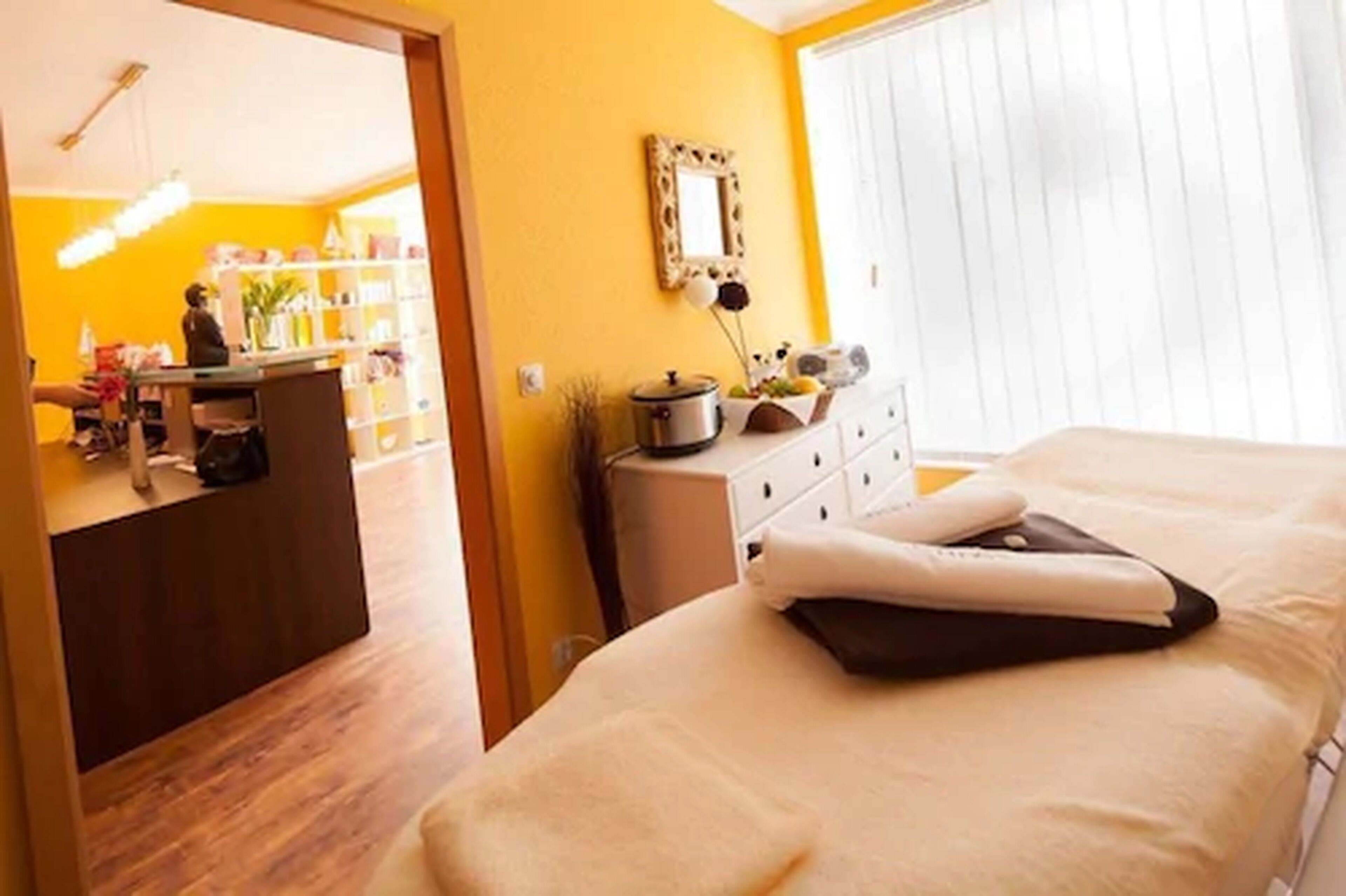 A hotel room with a bed, a dresser, a mirror, and a window with blinds.
