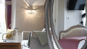 A hotel room with a bed, a chair, a desk, and a television on the wall. - Bowness Bay Suites - Adults only (Windermere)