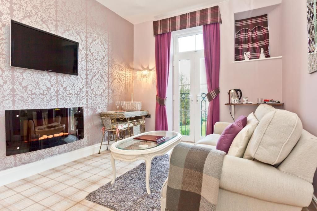 Een woonkamer met een flatscreen televisie, een bank, een salontafel en een open haard.