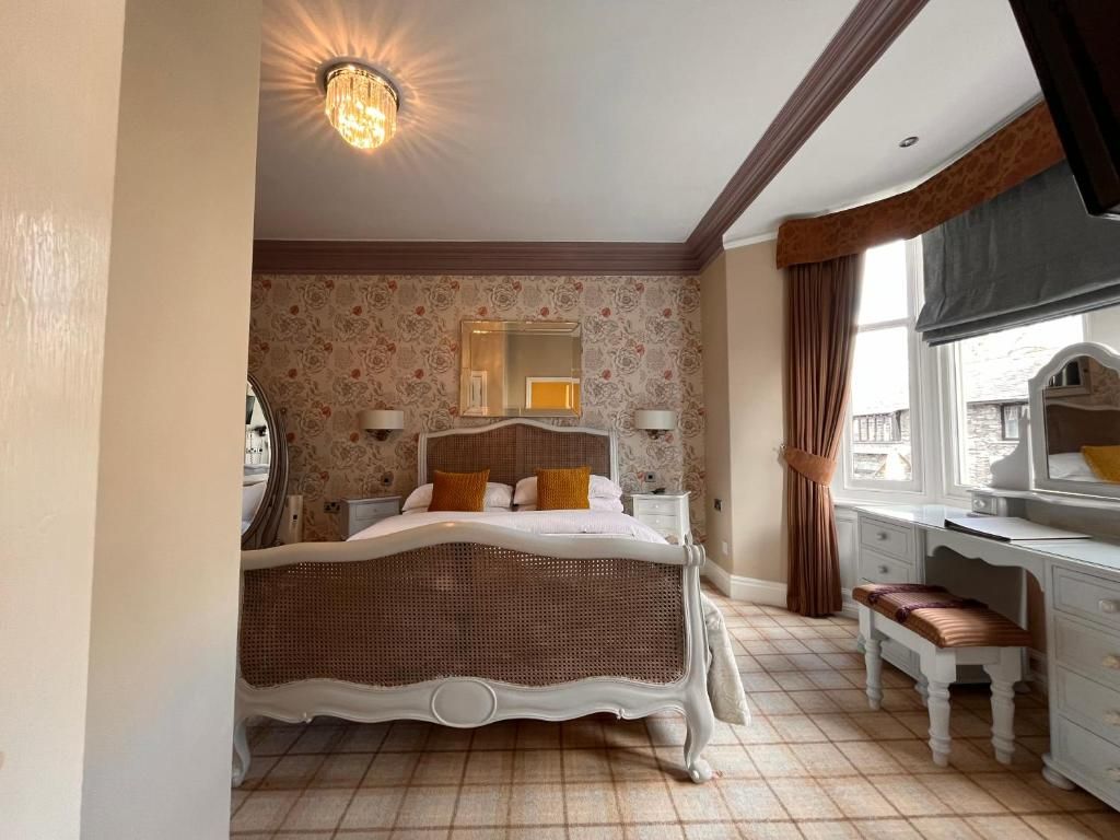 Une chambre avec un grand lit, une commode, un miroir et une fenêtre avec des rideaux.