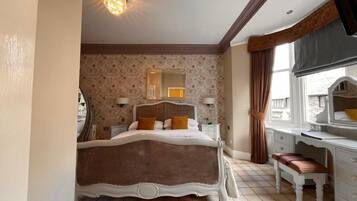 Une chambre avec un grand lit, une commode, un miroir et une fenêtre avec des rideaux.