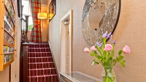 A staircase with a striped carpet, a mirror on the wall, and a vase with flowers on a console table. - Bowness Bay Suites - Adults only (Windermere)