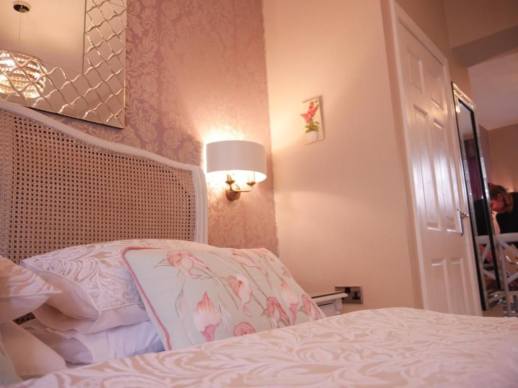 A bedroom with a bed, a wall-mounted lamp, and a door.