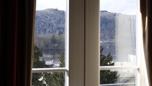 A view through a window of a lake with a forested hill in the background. - Bowness Bay Suites - Adults only (Windermere)