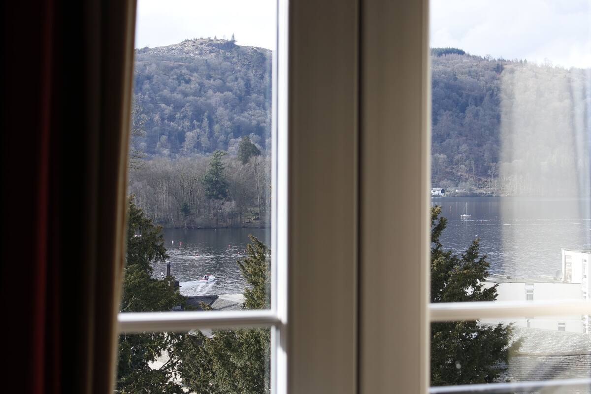 A view through a window of a lake with a forested hill in the background.
