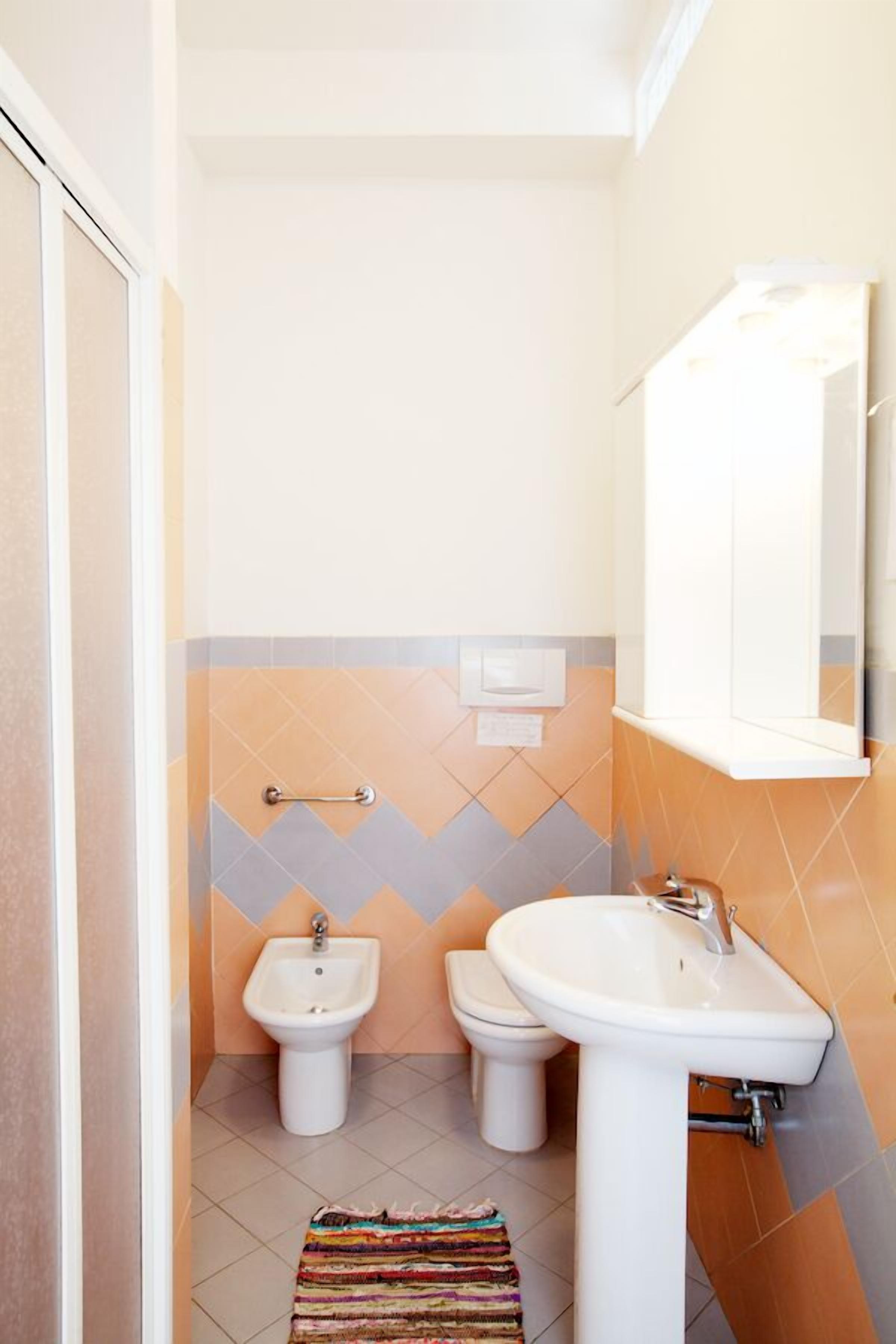 A small bathroom with a white sink, a bidet, and a toilet.