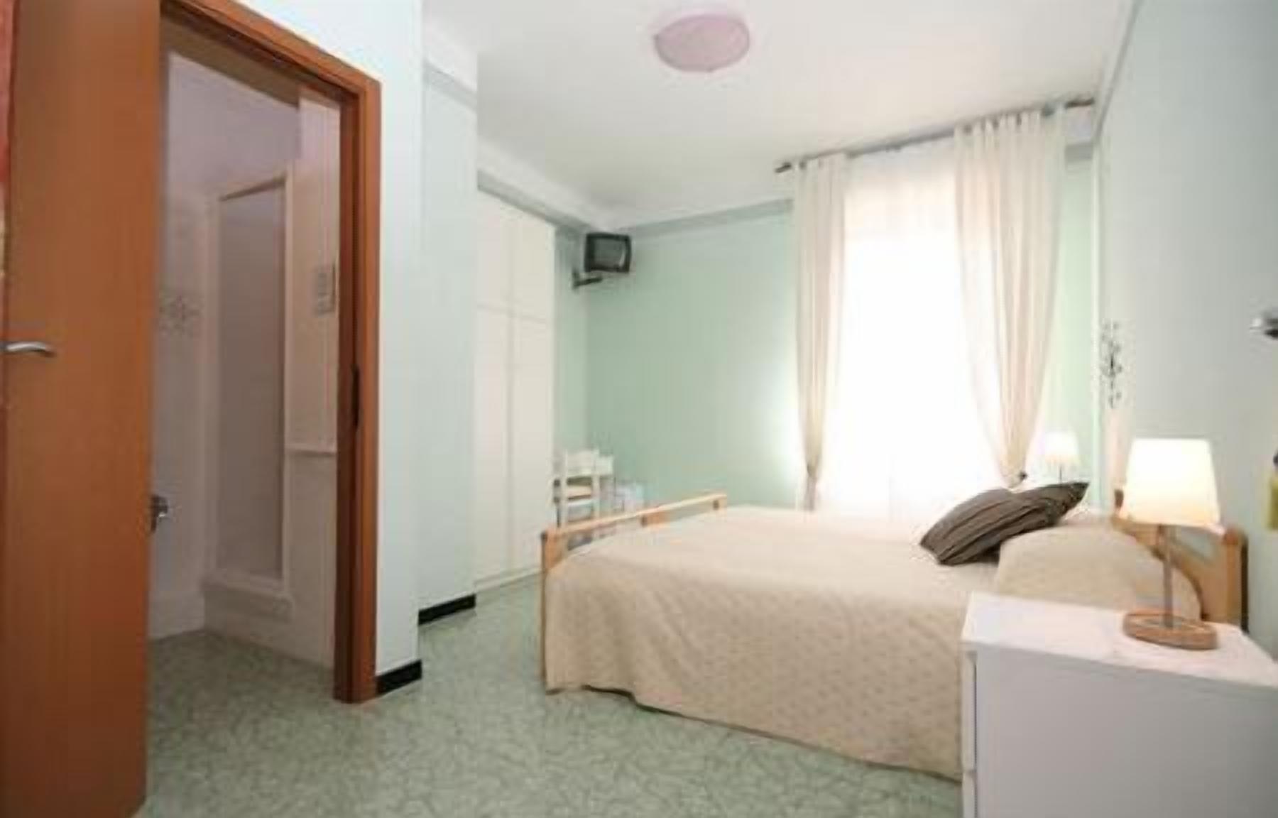 Een hotelkamer met een bed, een bureau, een stoel, een televisie en een raam met gordijnen.