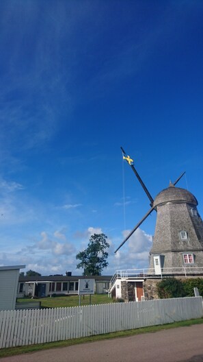 A windmill with a flag, a white picket fence, and a building with a sign. - Kvarnens Pensionat och Bed & Breakfast (Falkenberg)