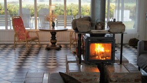A cozy room with a fireplace, checkered floor, and a view of the outdoors. - Kvarnens Pensionat och Bed & Breakfast (Falkenberg)