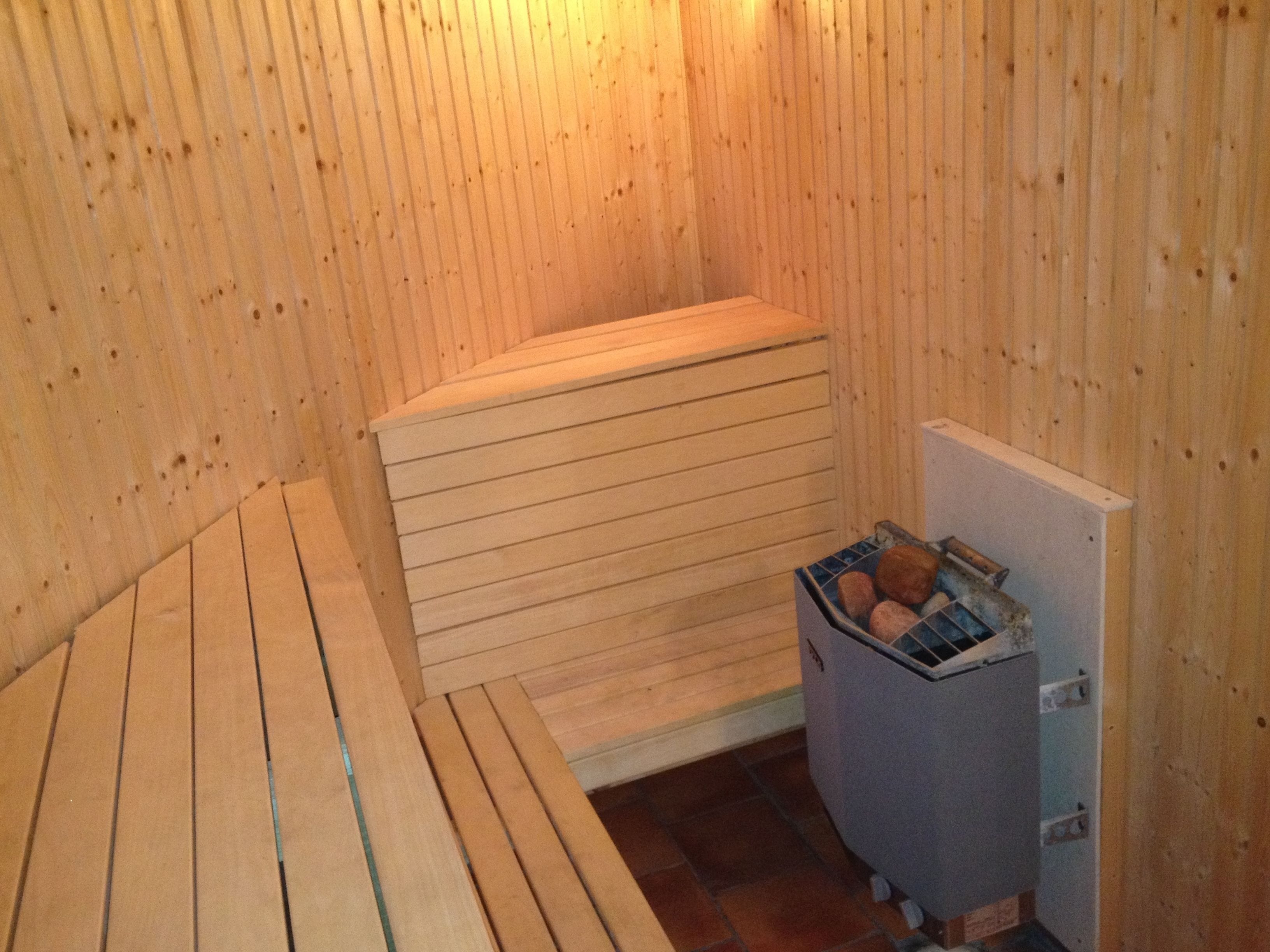 A sauna room with wooden benches and a small storage unit containing towels.