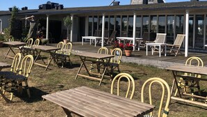 An outdoor seating area with tables and chairs, a windmill in the background, and a clear blue sky. - Kvarnens Pensionat och Bed & Breakfast (Falkenberg)