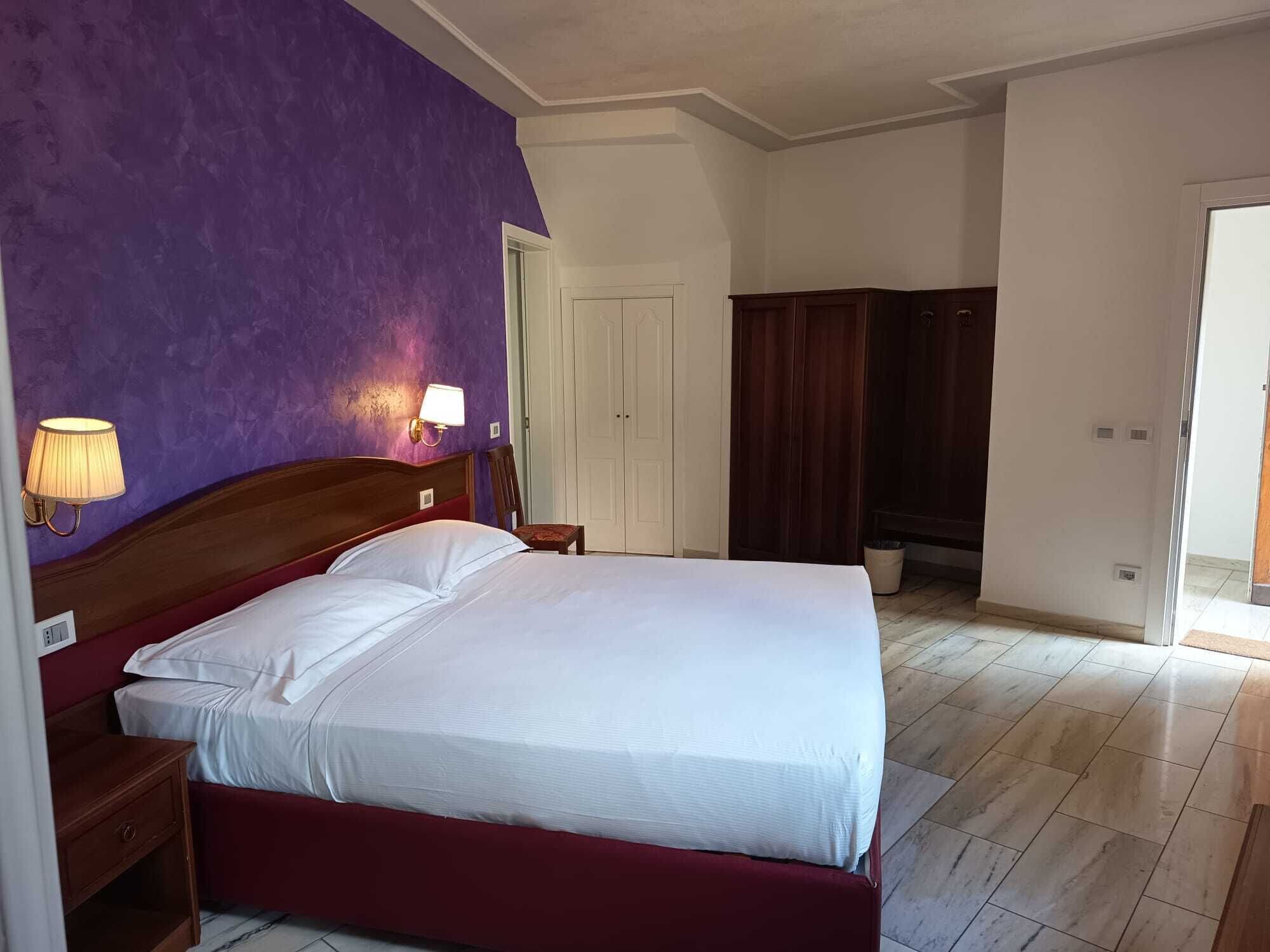 Un dormitorio con cama, mesita de noche, lámpara, armario y puerta.