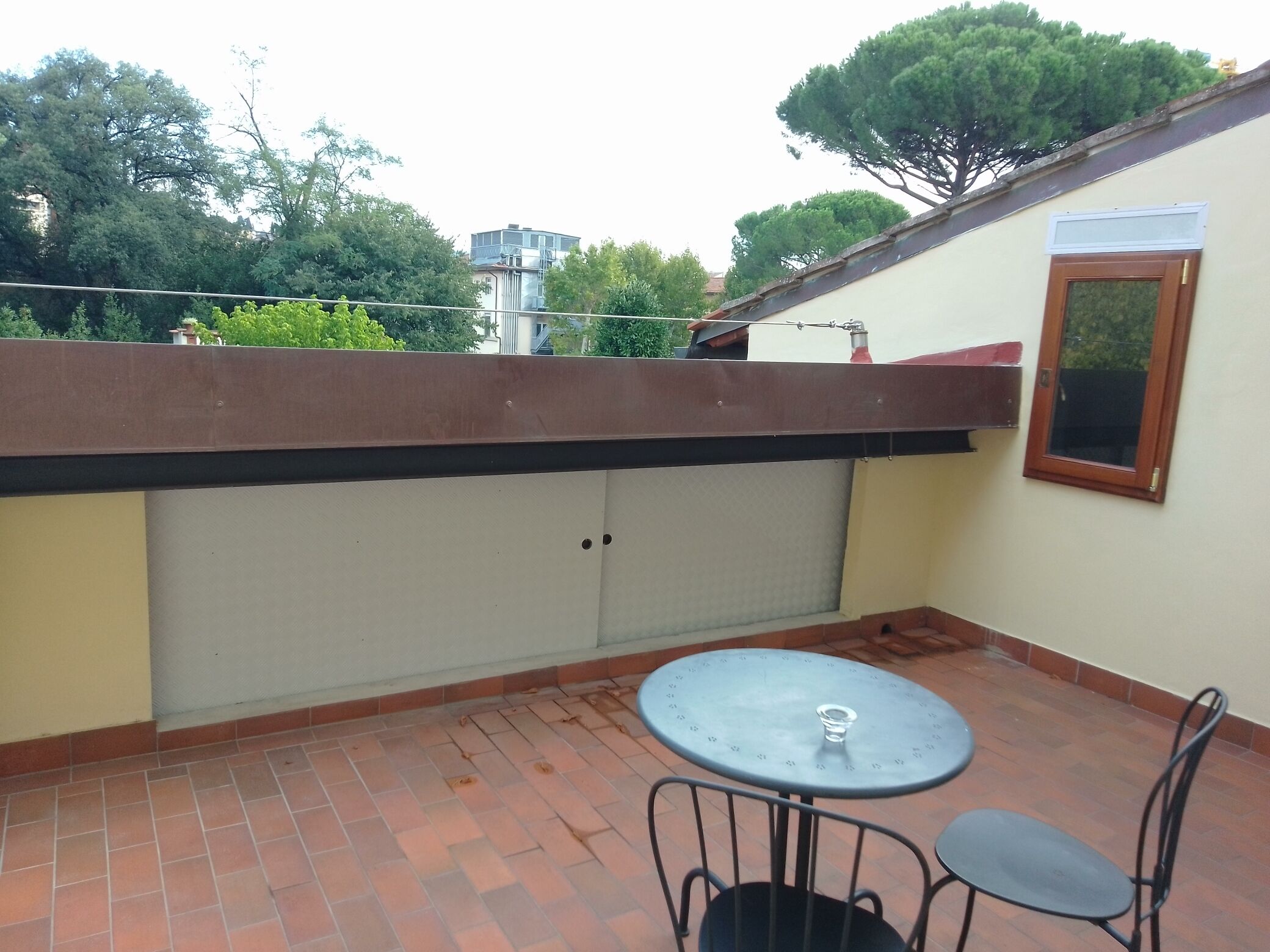 A small outdoor patio area with a round table and two chairs, a sliding door, and a window.