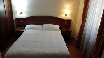 A hotel room with a large bed, two bedside tables, and two wall-mounted lamps.