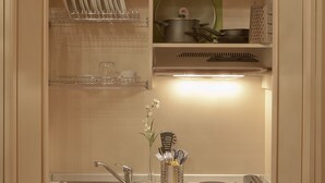 A compact kitchen with a sink, stove, and shelves for dishes and utensils. - Relais la Corte di Cloris (Florence)
