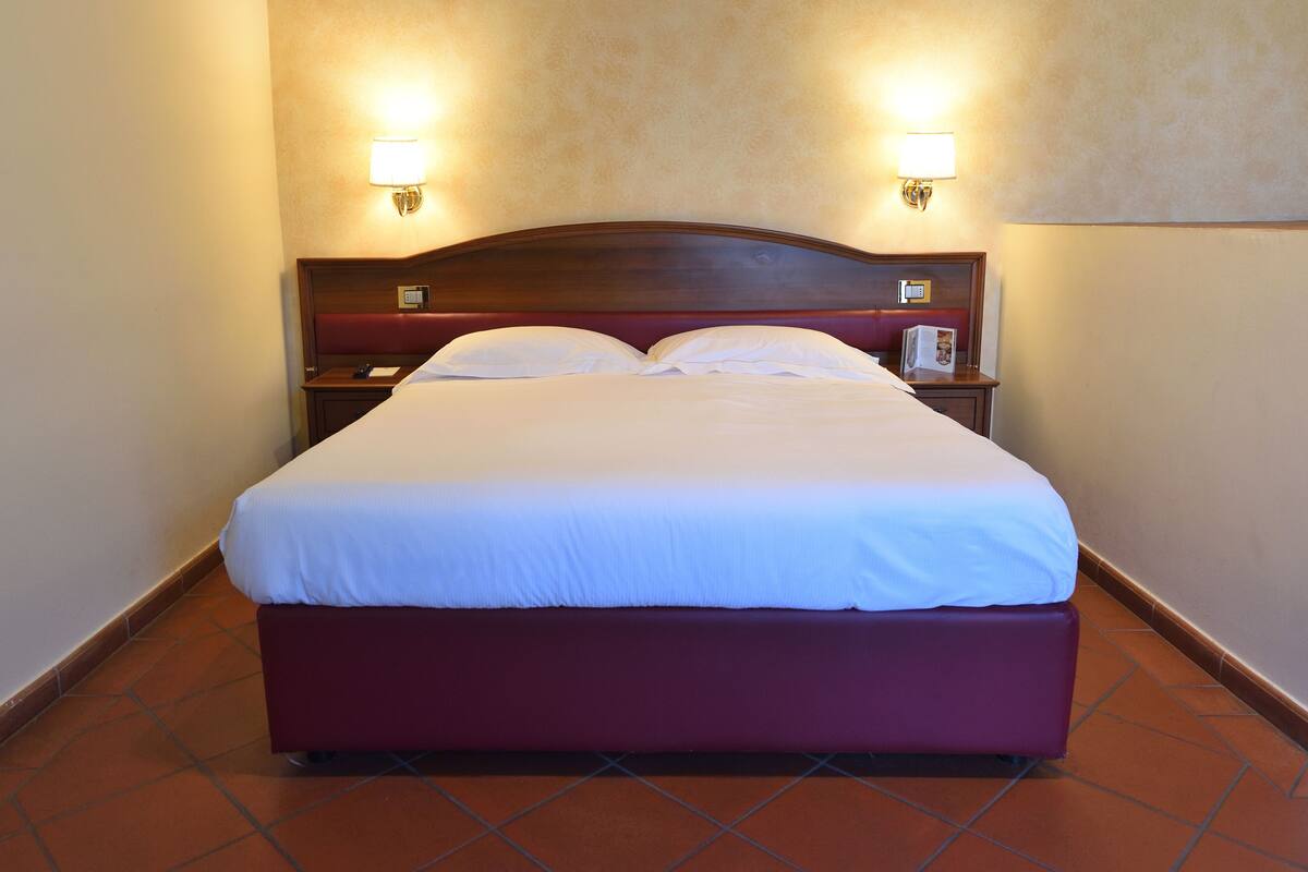 A neatly made bed with white linens and a wooden headboard, flanked by two bedside lamps.