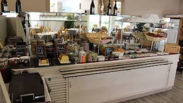 Een bakkerijvitrine met diverse gebakjes en drankjes.