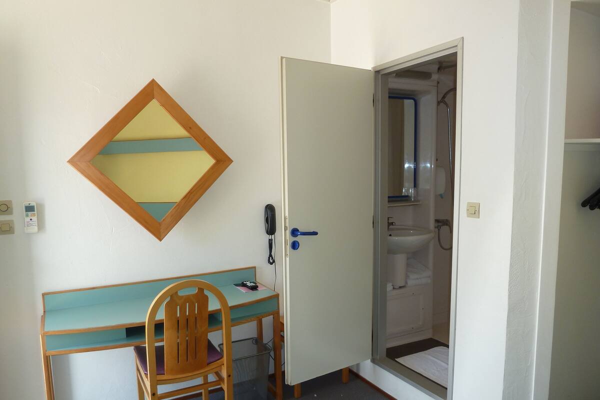Une pièce comprenant un bureau, une chaise et une porte donnant sur une salle de bain.
