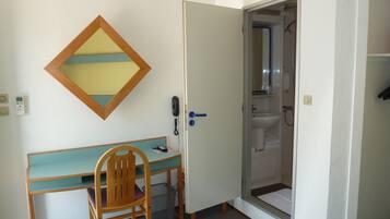 Habitació amb escriptori, cadira i porta que dóna a un bany.
