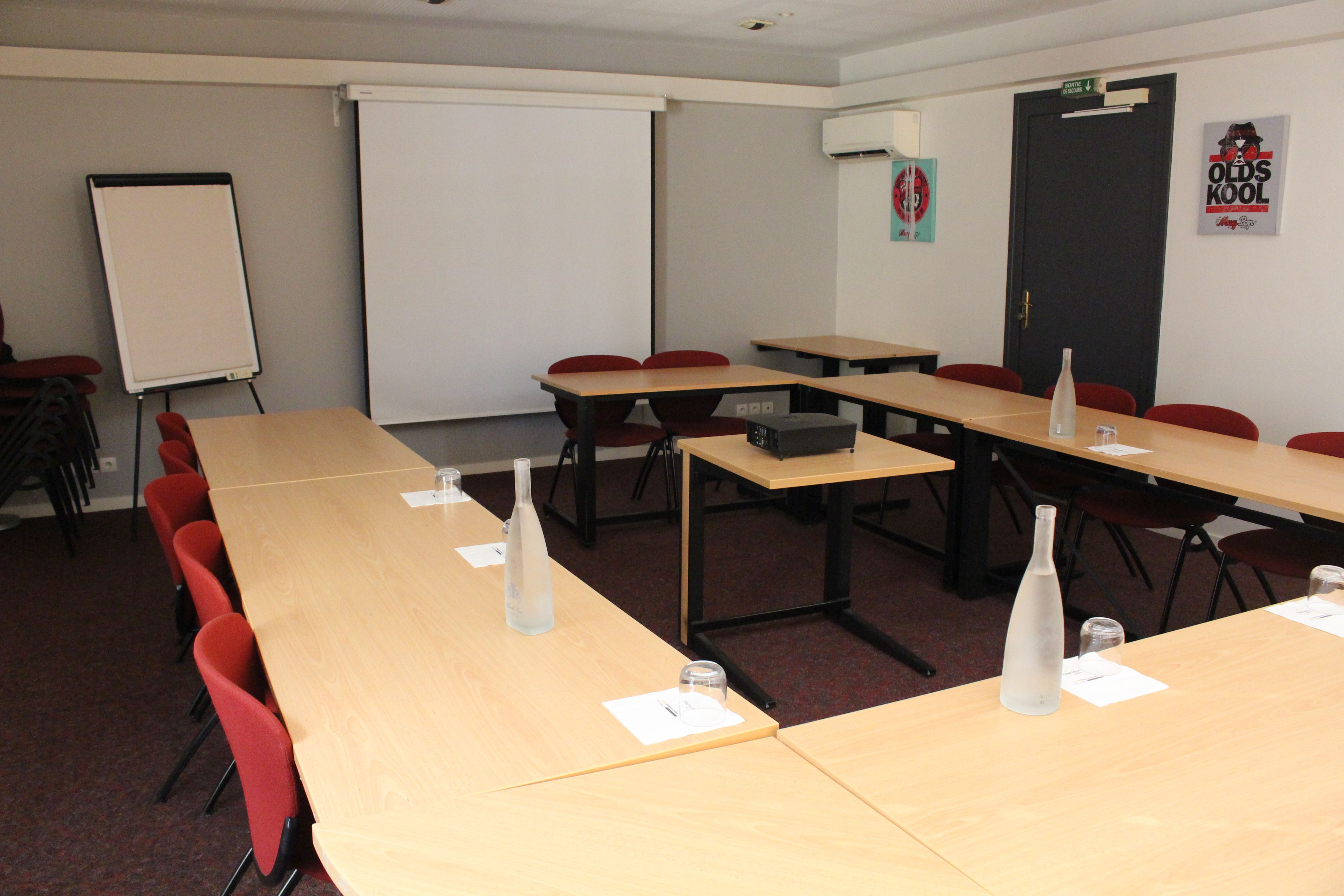A conference room with a whiteboard, projector, and tables with chairs.