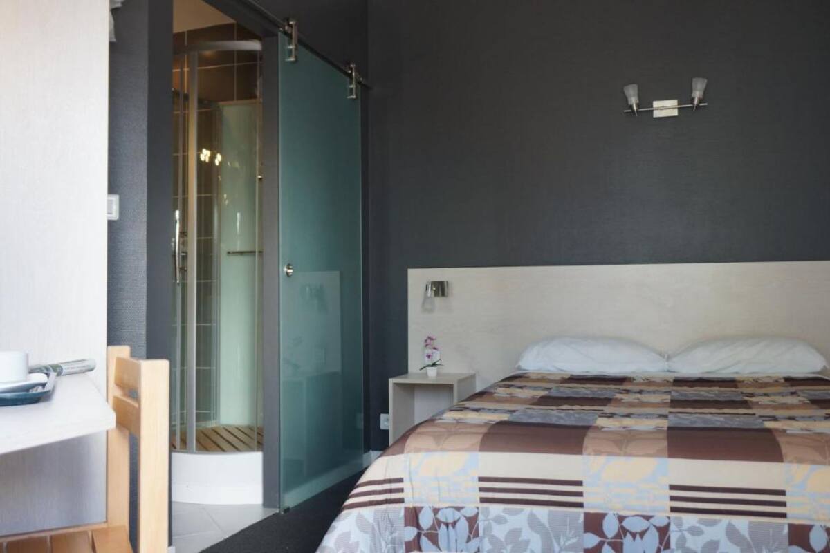 Une chambre d’hôtel avec un lit, un bureau et une douche en verre.