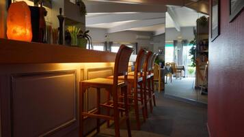 Un vestíbulo de hotel con una recepción, sillas de madera y vistas al comedor.