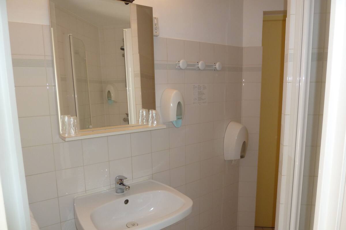 Une salle de bain équipée d’un lavabo, d’un miroir, d’un sèche-mains et d’un distributeur de serviettes en papier.