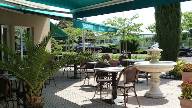 An outdoor seating area with tables and chairs, a stone fountain, and a sign for 'Le Moulin Restaurant'. - Hotel Restaurant Charme en Beaujolais (Belleville-en-Beaujolais)