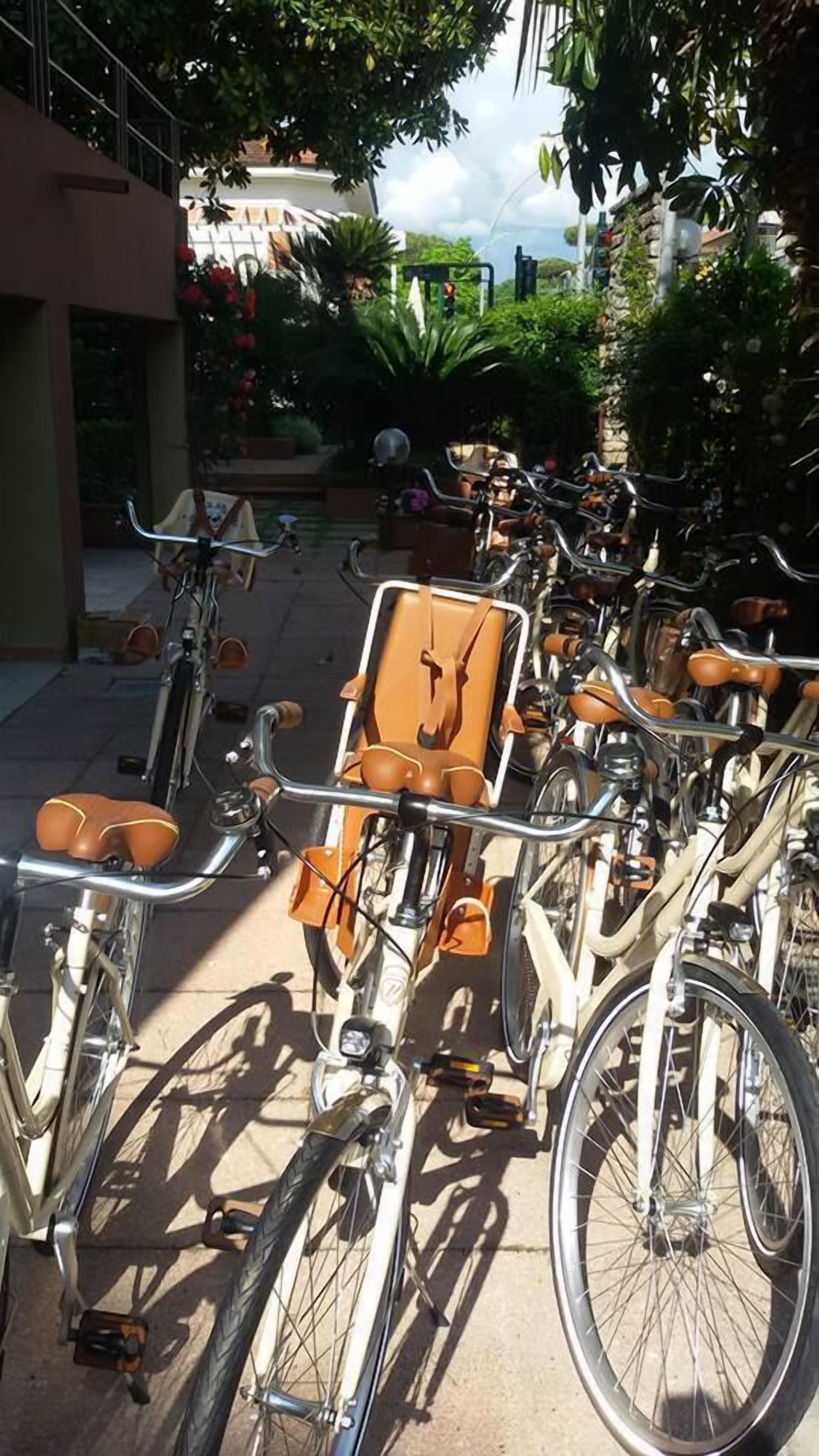 A row of bicycles parked in an outdoor area with a building in the background.