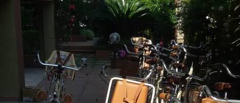 A row of bicycles parked in an outdoor area with a building in the background.