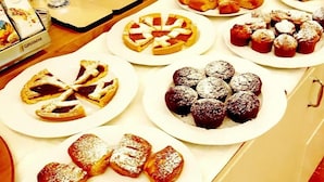 Variedad de pasteles y postres a la vista, incluyendo tartas, tartaletas y hojaldres, dispuestos sobre una barra.