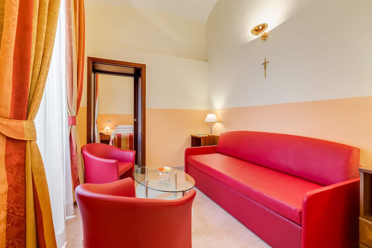 A room with a red sofa, a glass coffee table, and a lamp.