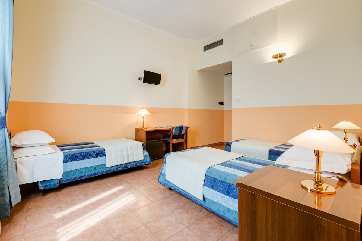 A hotel room with two beds, a desk, and a mirror.