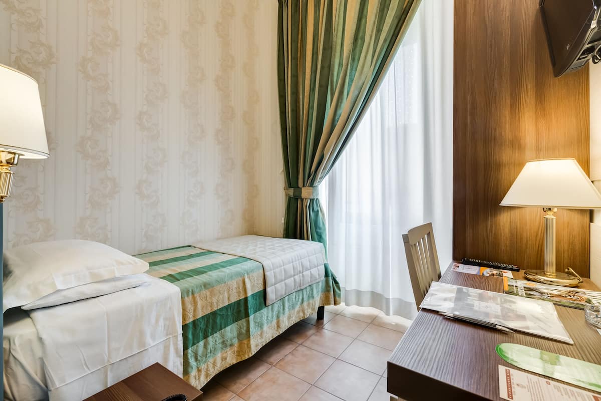 A hotel room with two beds, a desk, and a chair.
