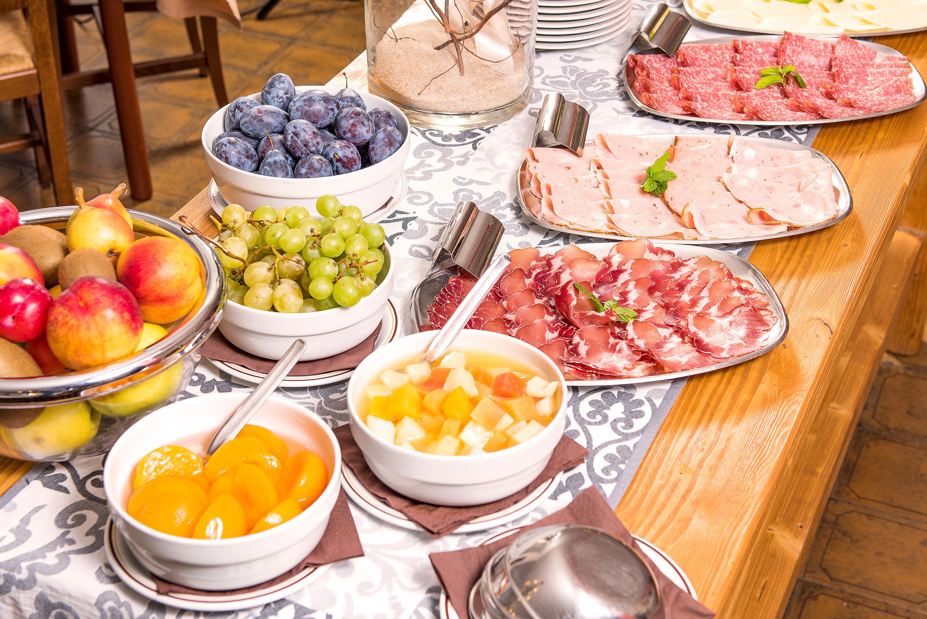 Una mesa con diversos alimentos, como frutas, quesos y embutidos.