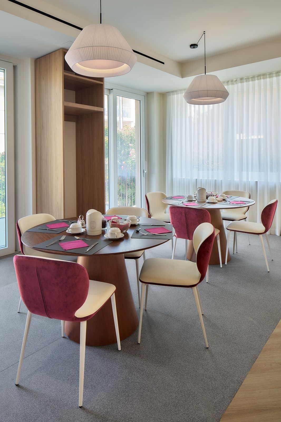 Un espace de restauration moderne avec des tables rondes, des chaises et des luminaires suspendus.