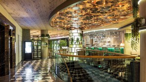 A modern hotel lobby with a checkered floor, a glass staircase, a bar area, and a ceiling with hanging umbrellas. - Opera Hotel Bosphorus - Preferred Hotels and Resorts (Istanbul)