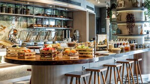 A modern kitchen with a central island, bar stools, and a variety of food items displayed on shelves and the island. - Opera Hotel Bosphorus - Preferred Hotels and Resorts (Istanbul)
