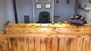 Un comptoir d’accueil avec un revêtement en bois, des certificats encadrés accrochés au mur et une petite plante placée à gauche.