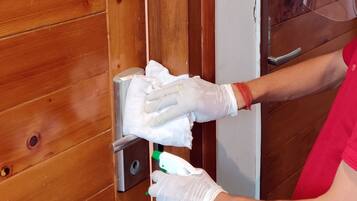 Una persona limpiando una puerta de madera con un trapo y un pulverizador.