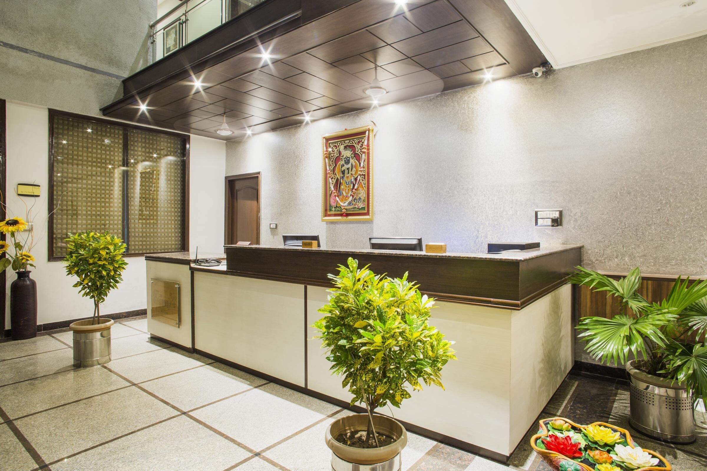 Zona de recepción con mostrador, plantas en macetas y un adorno mural.