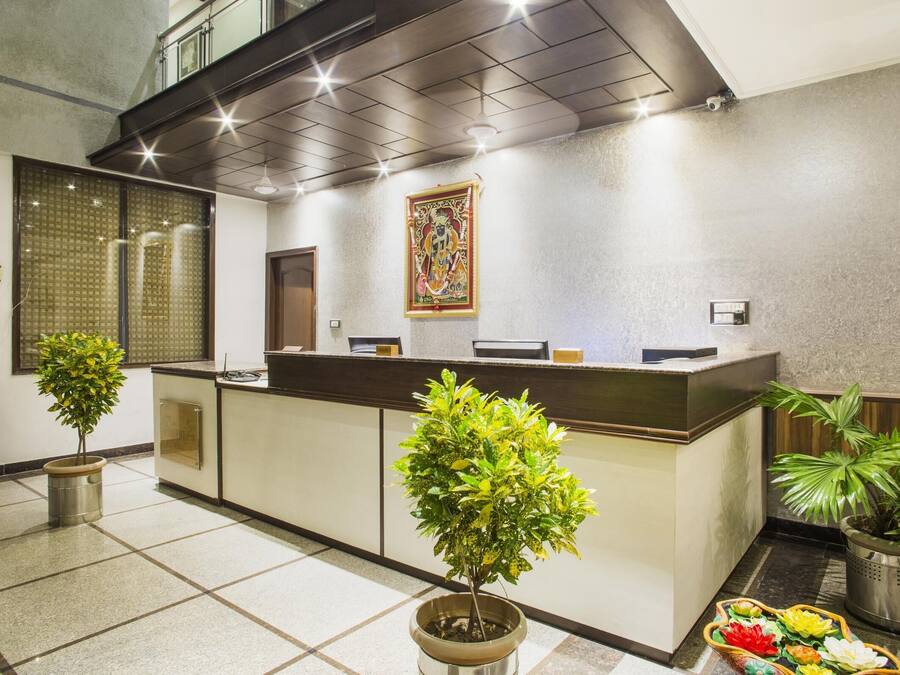 Zona de recepción con mostrador, plantas en macetas y un adorno mural.