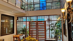 A hotel lobby with a high ceiling, a wooden partition with glass panels, and a foosball table.