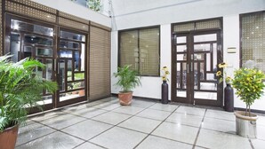 A clean, tiled courtyard with potted plants and large doors leading to rooms.