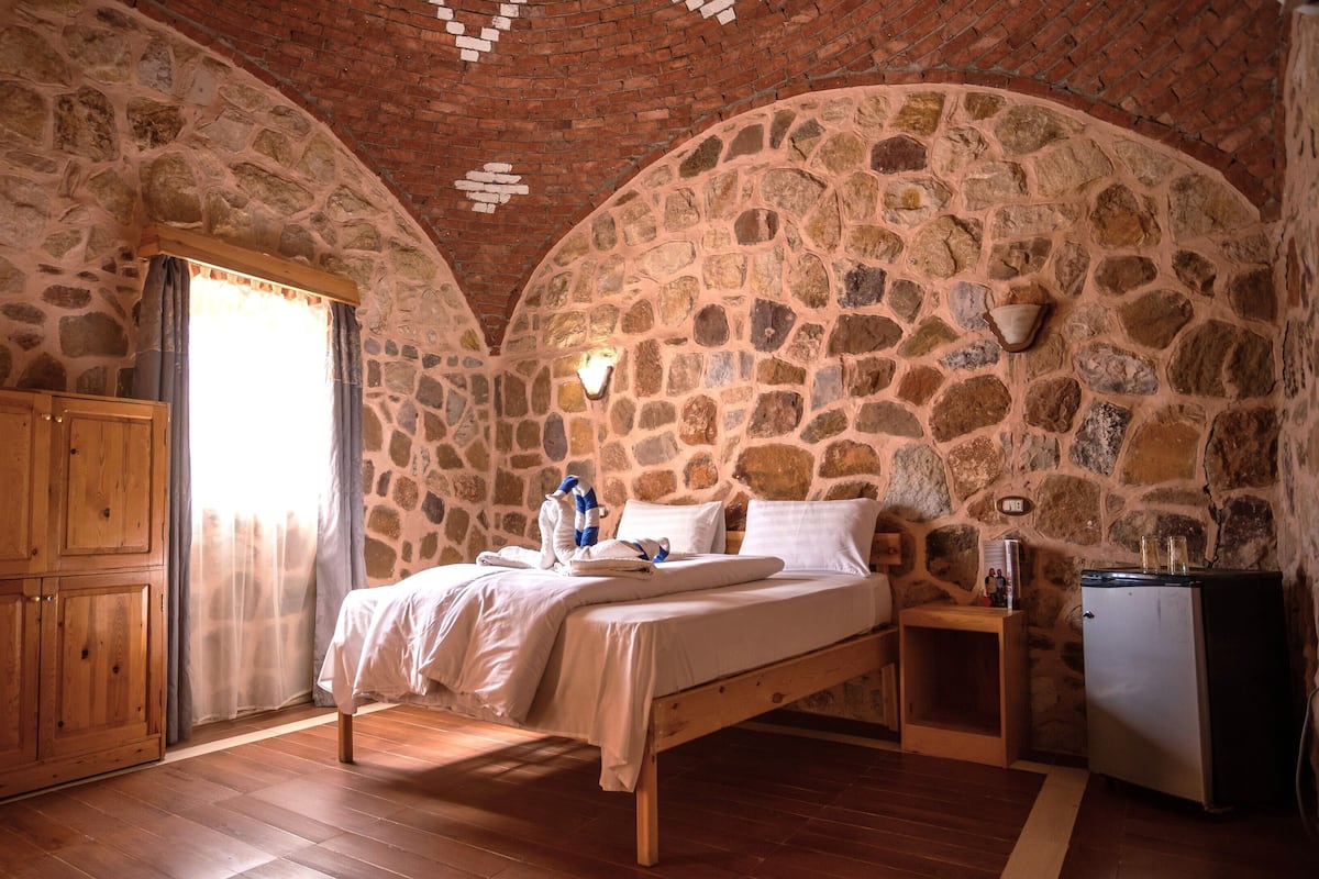 Ein Schlafzimmer mit Stehwänden, einem hölzernen Bett, einem Kleiderschrank und einem kleinen Kühlschrank.
