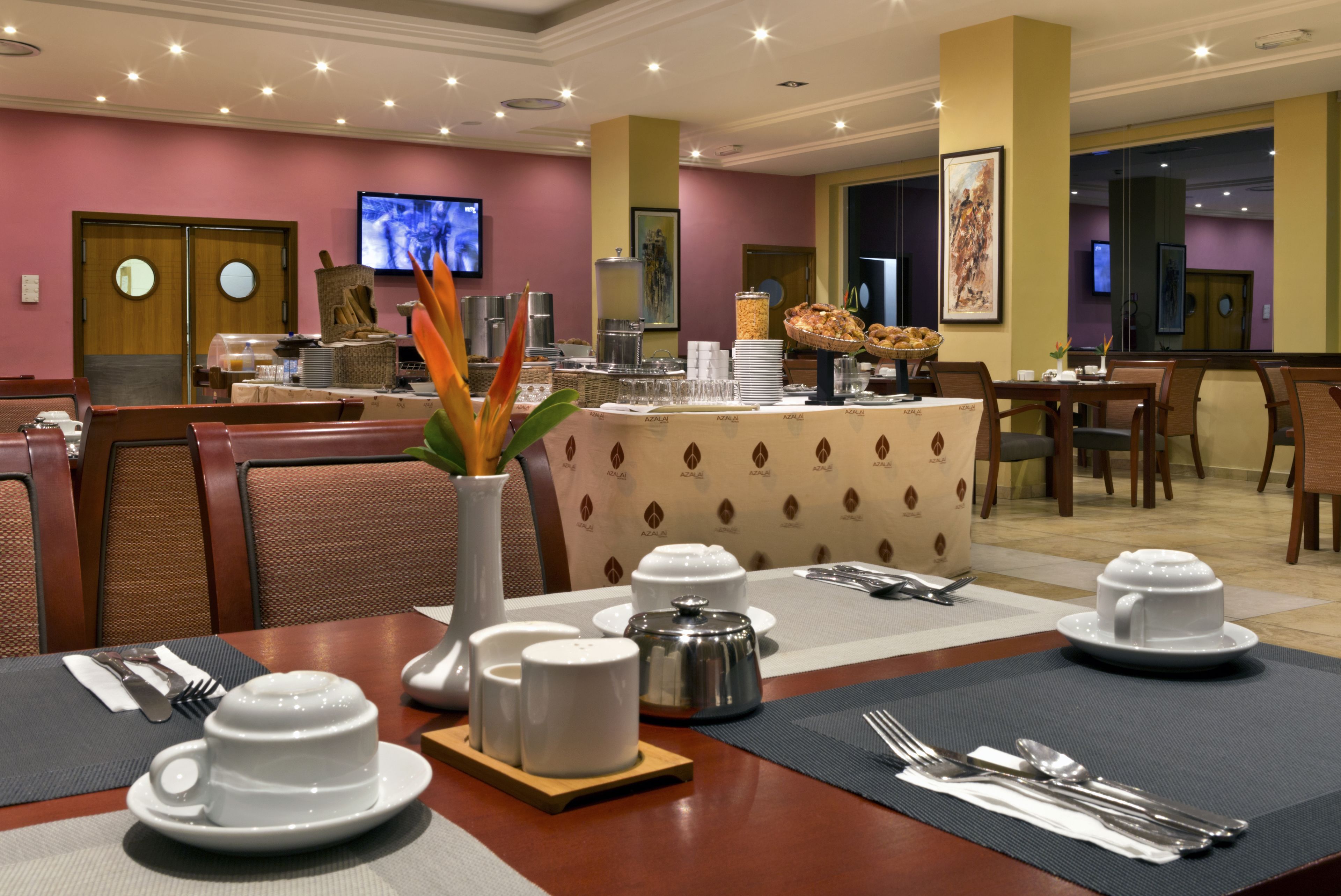 Area ristorazione hotel con buffet, ampia scelta di cibi e schermo televisivo sullo sfondo.