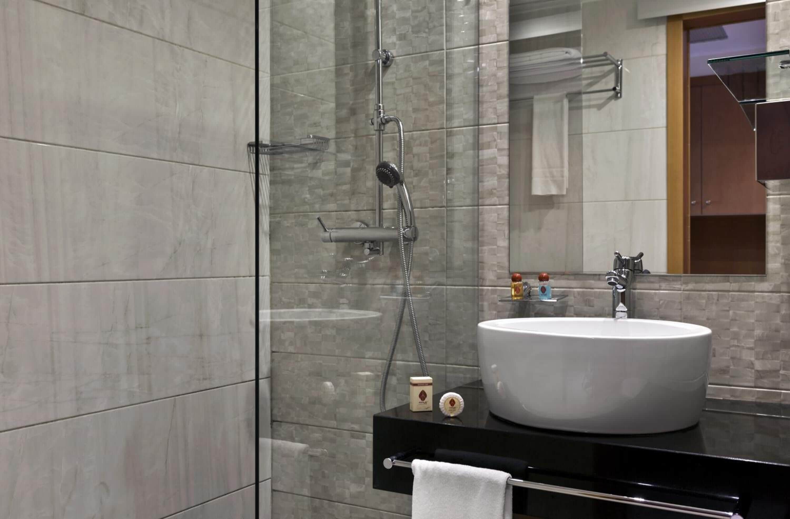 A modern bathroom with a large white sink, a glass-enclosed shower, and a mirror above the sink.