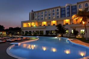 A hotel with a large swimming pool, lounge areas, and a well-lit building facade. - Azalaï Hotel Cotonou (Cotonou)