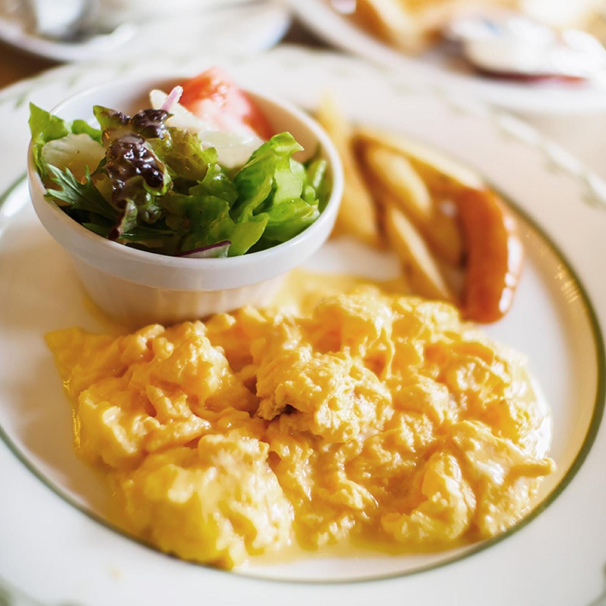 Scrambled eggs, a side salad, and French fries on a plate.